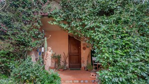 A rustic entrance with a wooden door, potted plants, and a statue. - Casa Bice Room with Private Terrace and Wi-Fi (Marcialla)