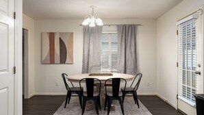 A dining area with a round table, four chairs, a chandelier, and a window with blinds. - Family Gem in Pelham 3BR/2Bath 1 LEVEL Pet friendly home (Pelham)