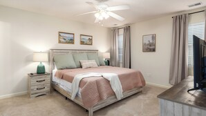 A bedroom with a bed, bedside tables, a ceiling fan, and wall-mounted artwork. - Family Gem in Pelham 3BR/2Bath 1 LEVEL Pet friendly home (Pelham)
