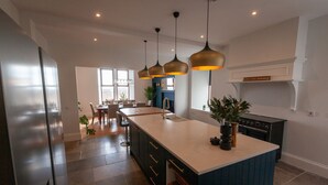 A modern kitchen with a central island, pendant lighting, and a dining area with natural light.