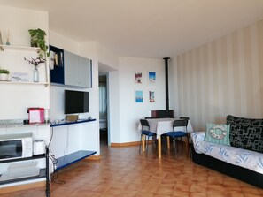 A compact living space with a kitchenette, dining area, and a sofa.