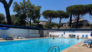 A swimming pool with clear blue water, surrounded by lounge chairs and umbrellas. - Bright villa with pool in Grimaud (Grimaud)