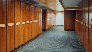 Um corredor com armários de madeira e piso texturizado, que leva a um quarto com porta branca.