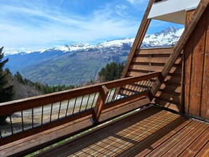Eine Holztreppe führt zu einem Balkon mit Blick auf schneebedeckte Berge.