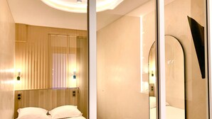 Una camera d'hotel moderna con un letto grande, una testiera in legno e un ampio specchio.