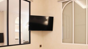 Una stanza con una TV a schermo piatto a parete, uno specchio grande e una finestra con vetro smerigliato.