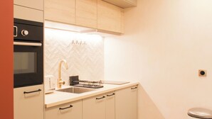 Una cucina moderna con forno integrato, lavello in acciaio inossidabile e backsplash con motivo a spina di pesce.