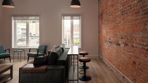 A modern interior with a brick wall, a long table, and green seating.