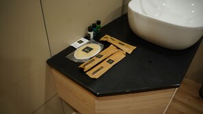A bathroom counter with a sink, a toothbrush holder, and a package labeled "VOX." - Vox Holiday (Palakkad)