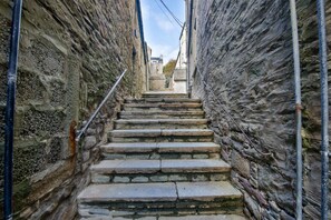 Una estrecha escalera de piedra en un edificio histórico, con vistas al pueblo a lo lejos.