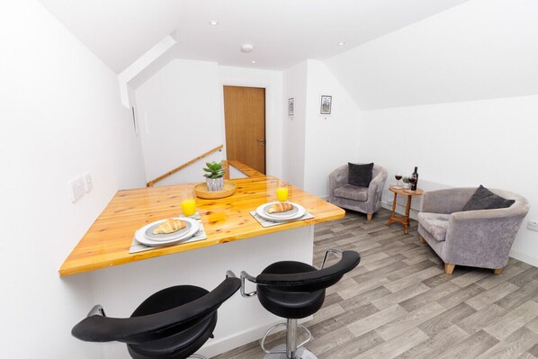 A compact living space with a kitchenette, a dining area, and a seating area with two armchairs and a small table.