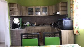 Cocina compacta con comedor, que incluye microondas, cocina y sillas verdes.