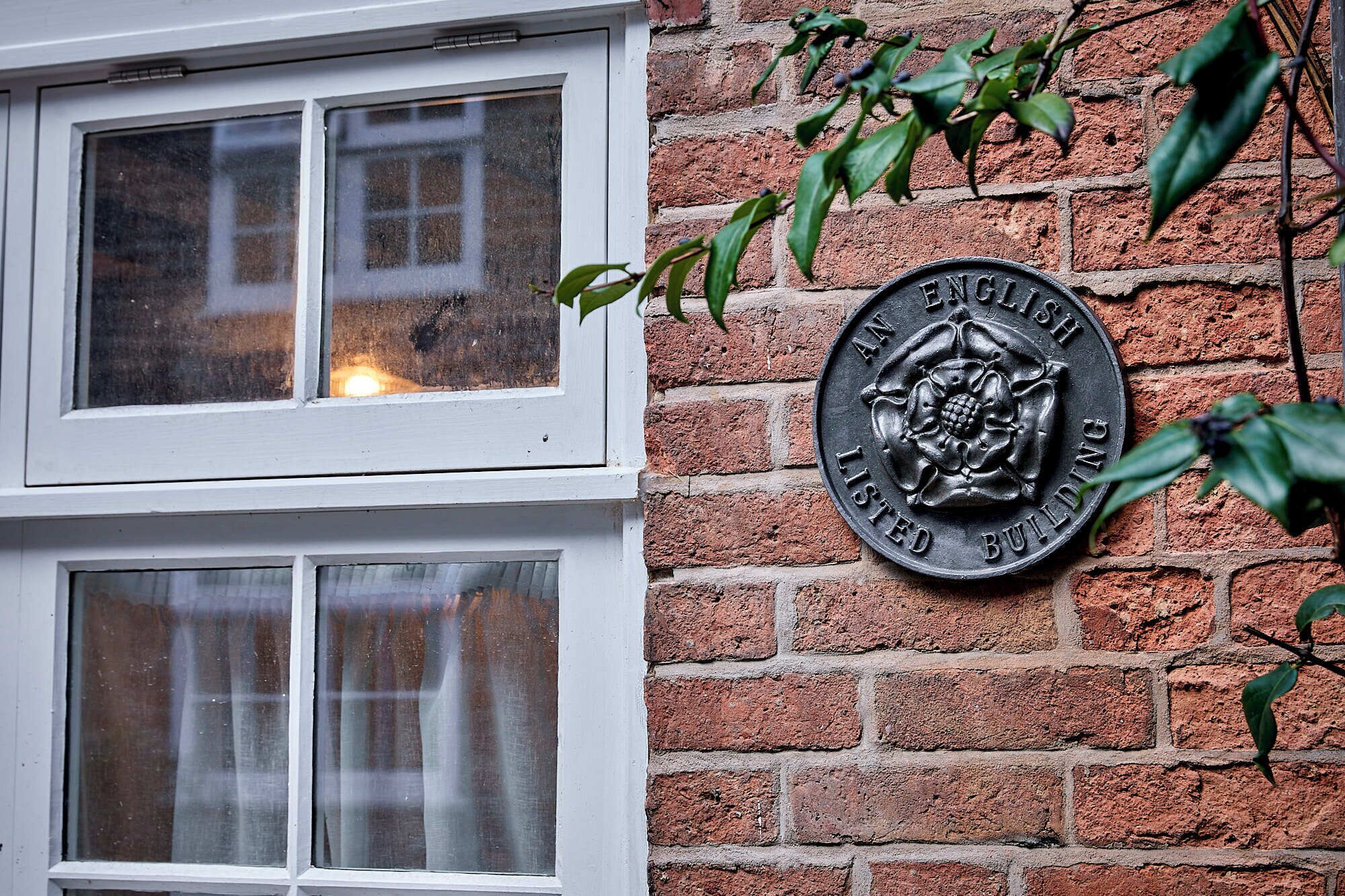 A brick wall with a plaque reading "AN ENGLISH LISTED BUILDING."