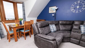 A modern living room with a sectional sofa, wooden dining table, and chairs.