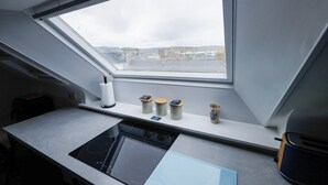 A kitchen with a skylight, a built-in stove, and a window with a view of a cityscape.