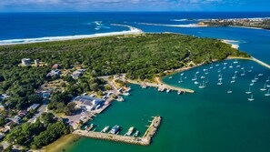 Luftaufnahme einer Küstenregion mit einem Yachthafen, Booten und einem Wohngebiet mit Häusern und einem Gebäude mit Solaranlage.