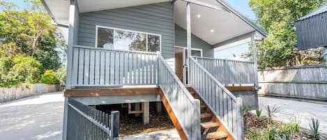 A two-story house with a covered front porch, a staircase, and a fenced yard.