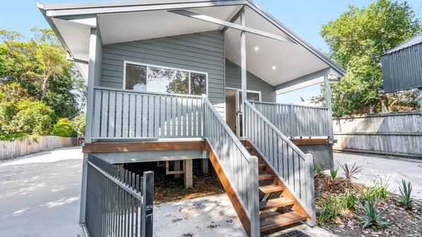 A two-story house with a covered front porch, a staircase, and a fenced yard.