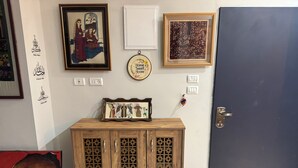 A room with a wooden cabinet, a door, and various framed artworks on the wall. - Perfect 2-bedroom apartment with AC in charming Bethlehem (Bethlehem)
