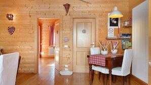 A wooden interior with a dining table, chairs, a hanging light fixture, and a door with a sign. - 'Gratacul' Room with Mountain View, Shared Terrace (Valtournenche)
