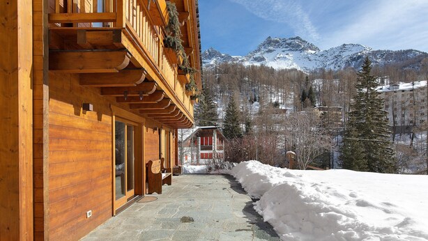 A wooden building with a stone pathway leading to a snow-covered area, with mountains in the background. - 'Gratacul' Room with Mountain View, Shared Terrace (Valtournenche)