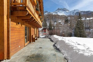 A wooden building with a stone pathway leading to a snow-covered area, with mountains in the background. - 'Gratacul' Room with Mountain View, Shared Terrace (Valtournenche)