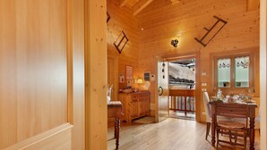 A wooden interior with a kitchen area, dining table, and a view through a doorway. - 'Gratacul' Room with Mountain View, Shared Terrace (Valtournenche)