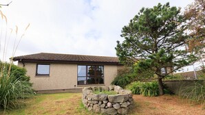 A two-story house with a stone wall and a large tree in the front yard. - NEW to VRBO: Peaceful Lerwick Stay; Large Garden, Isles Views (Lerwick)