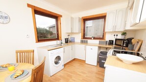 A compact kitchen with a washing machine, a microwave, and a sink. - NEW to VRBO: Peaceful Lerwick Stay; Large Garden, Isles Views (Lerwick)