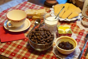 A table with a bowl of cereal, a glass of milk, a cup, and a plate of cheese slices. - Gratacul Room with Mountain View, Shared Terrace (Valtournenche)