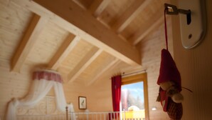 Un dormitorio con techo de madera, cama con dosel, cortina roja y vista al exterior.