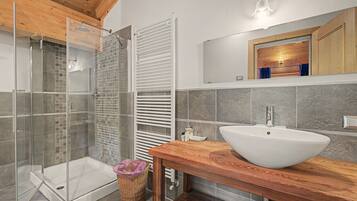Une salle de bain moderne avec une douche à parois de verre, un meuble-lavabo en bois doté d’un grand évier et un porte-serviettes.