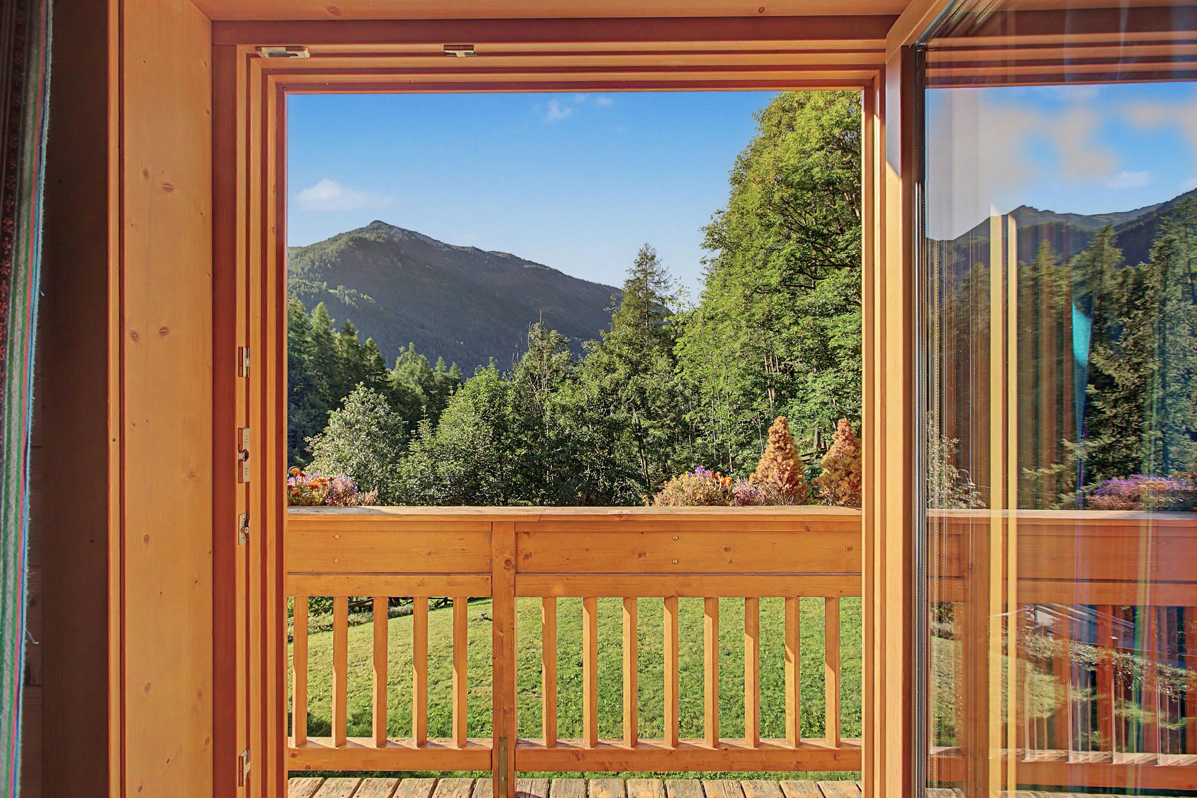 Une terrasse en bois offrant une vue sur un paysage montagneux et une forêt dense.