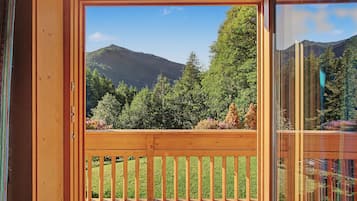 Une terrasse en bois offrant une vue sur un paysage montagneux et une forêt dense.