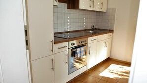 Een keuken met witte kasten, een roestvrijstalen spoelbak en een betegelde achterwand.