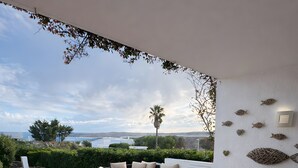 Une terrasse avec une table et des chaises, un canapé et une vue sur la mer.