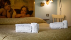 A bed with neatly folded white towels, a wall with a painting, and a wall-mounted light fixture. - Room 'Camera 1 - Il Maggio' with Shared Pool, Wi-Fi and Air Conditioning (Manciano)