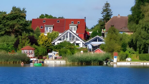 Une propriété au bord du lac, avec un bâtiment rouge, une maison blanche et un petit quai.