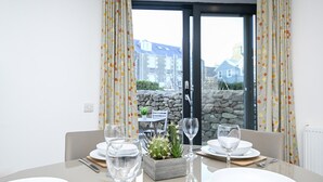 A dining table set with white plates, glasses, and cutlery, with a cactus centerpiece. - NEW to VRBO: Elegant Lerwick Townhouse • Harbour Views + Patio (Lerwick)