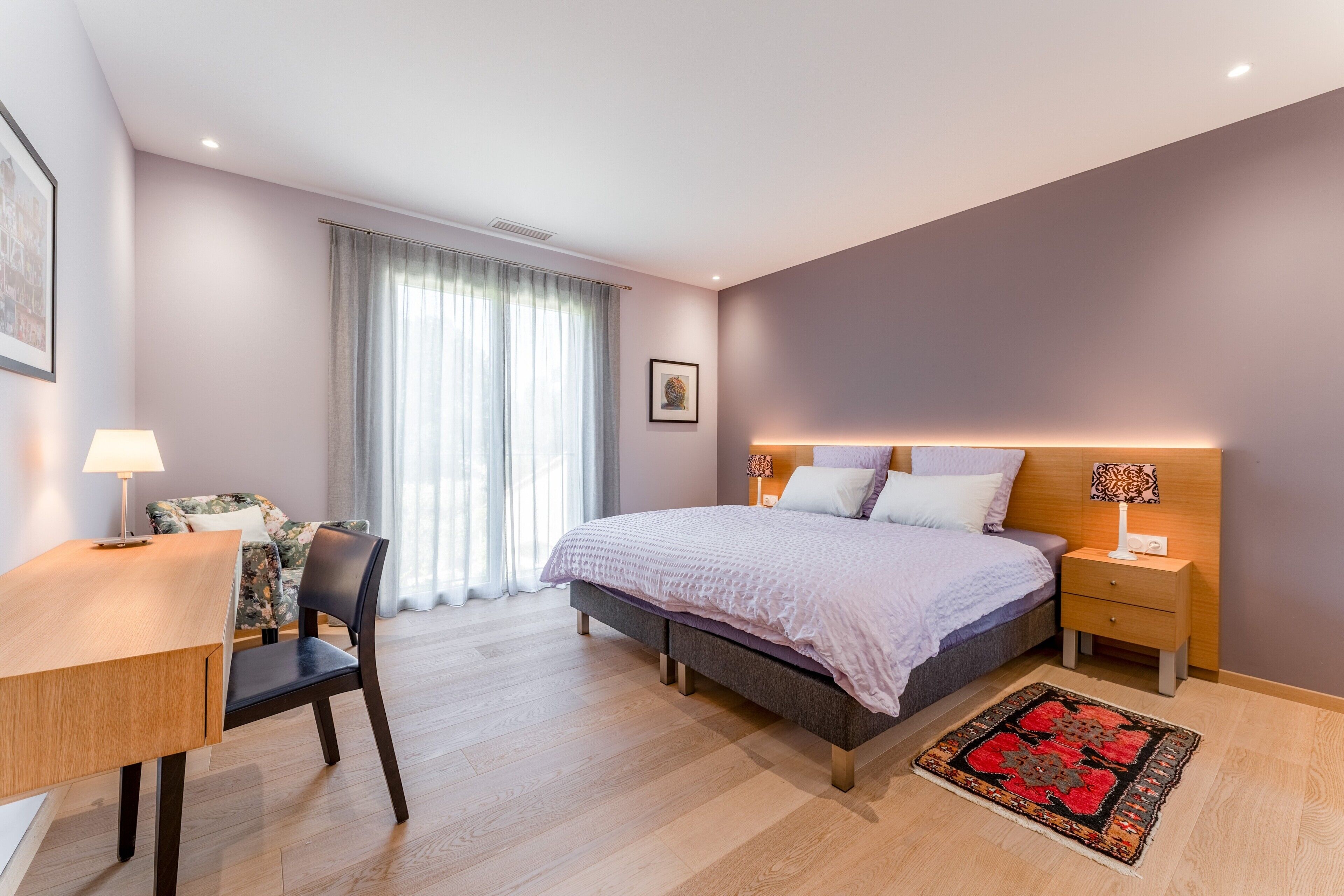 A modern bedroom with a bed, bedside tables, a desk, and a chair.