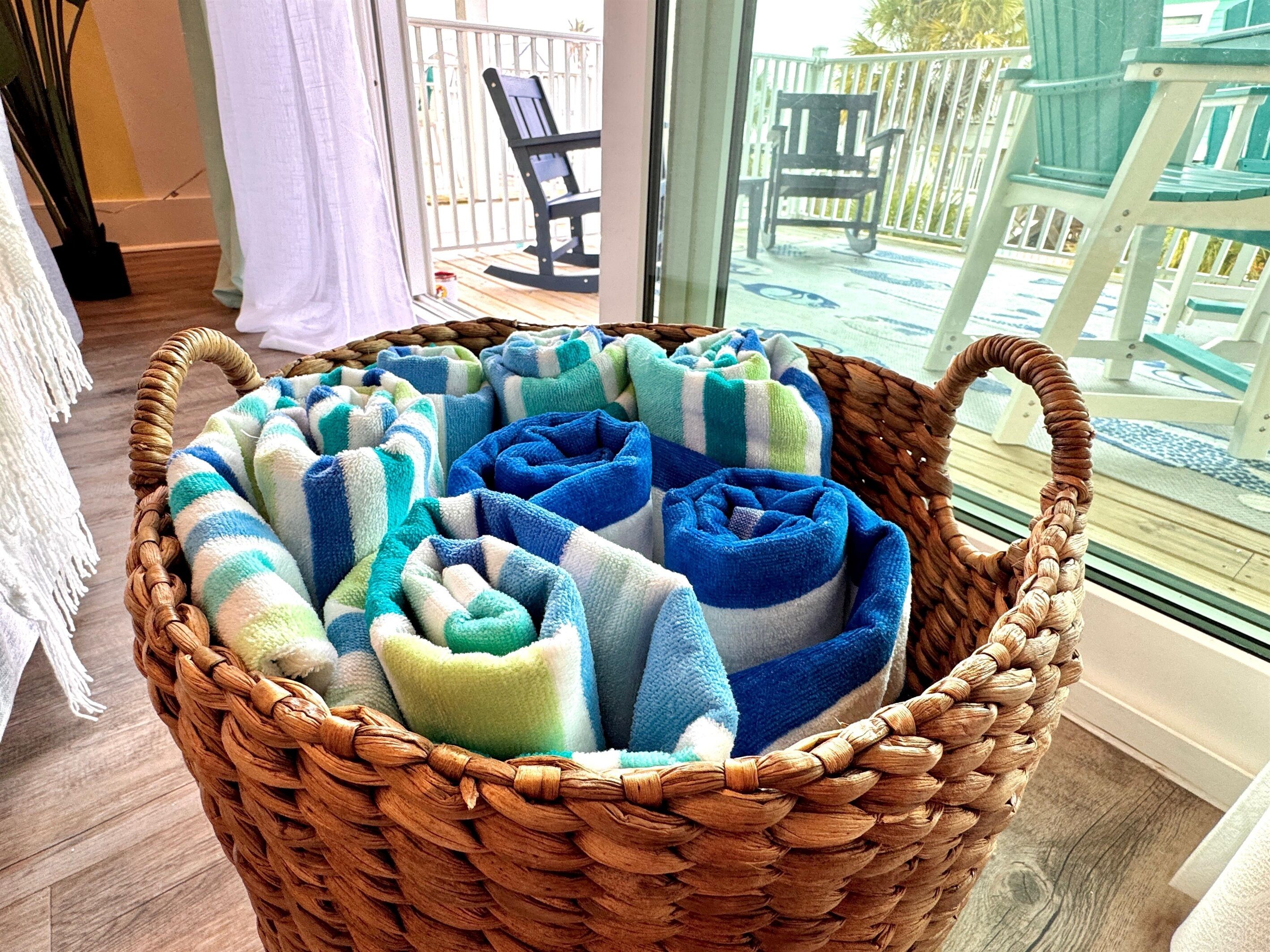 A wicker basket filled with rolled towels in various colors.