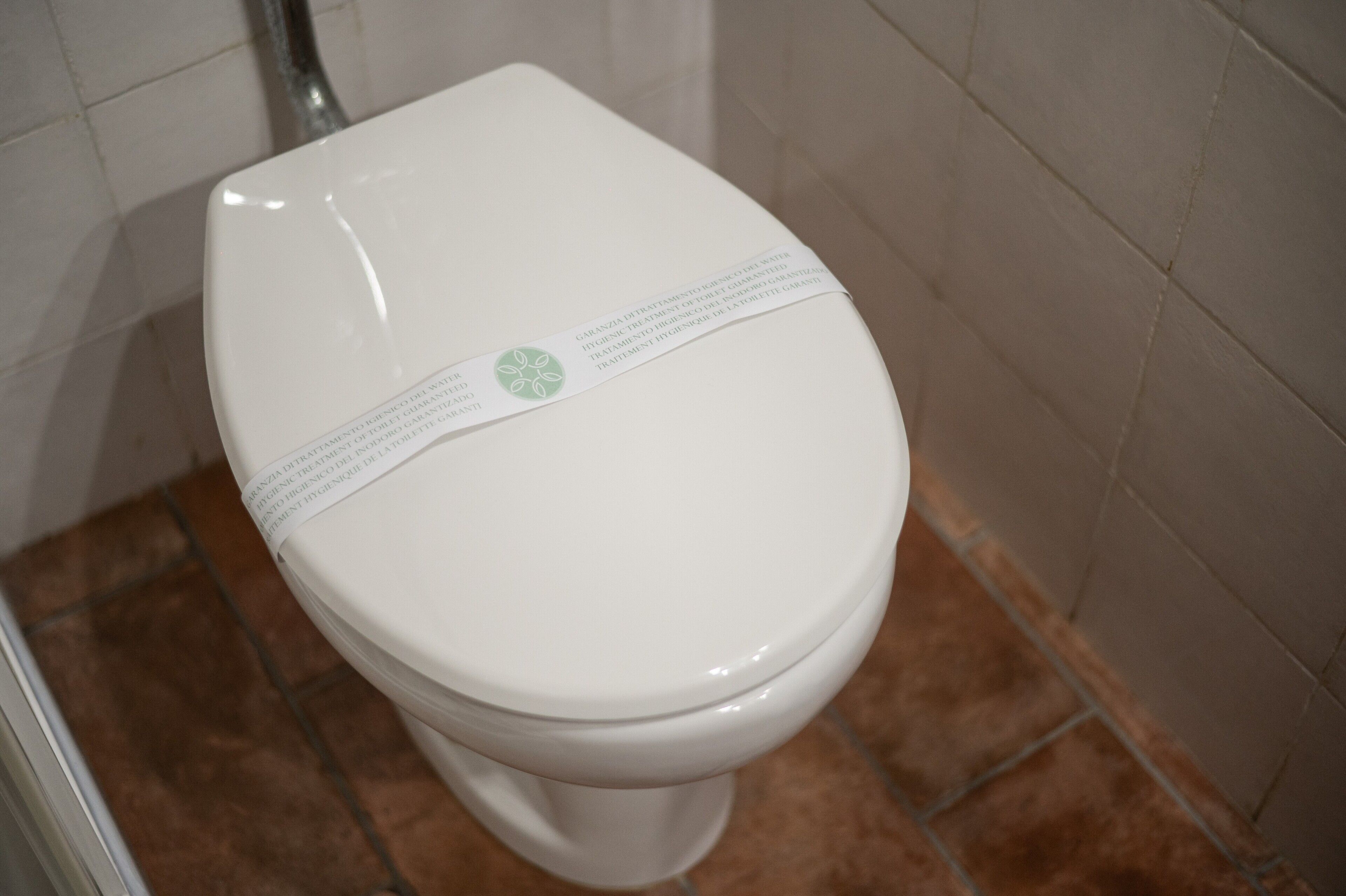 A white toilet with a green circular sticker and a white band across the seat.