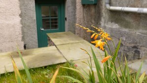 Un bâtiment en pierre avec une porte verte et un rebord en béton à l’avant.