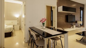 Moderni hotellihuone, jossa on ruokailutila, sänky, televisio ja kylpyhuone.