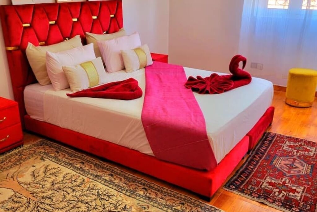 A bed with a red headboard, white bedding, and a red blanket.