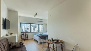 A compact hotel room with a bed, a small table with a glass, and a TV mounted on the wall. - Studio in Barra 600 m From the Beach Bsf0806 (Salvador)
