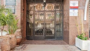 Ein Gebäudeeingang mit einem großen Metallgitter, Blumentöpfen und einem Ziegelweg, der zur Tür führt.