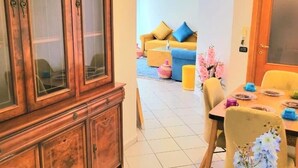 Ein Essbereich mit einem Holzkabinett, einem für zwei gedeckten Tisch und einer Couch im Hintergrund.