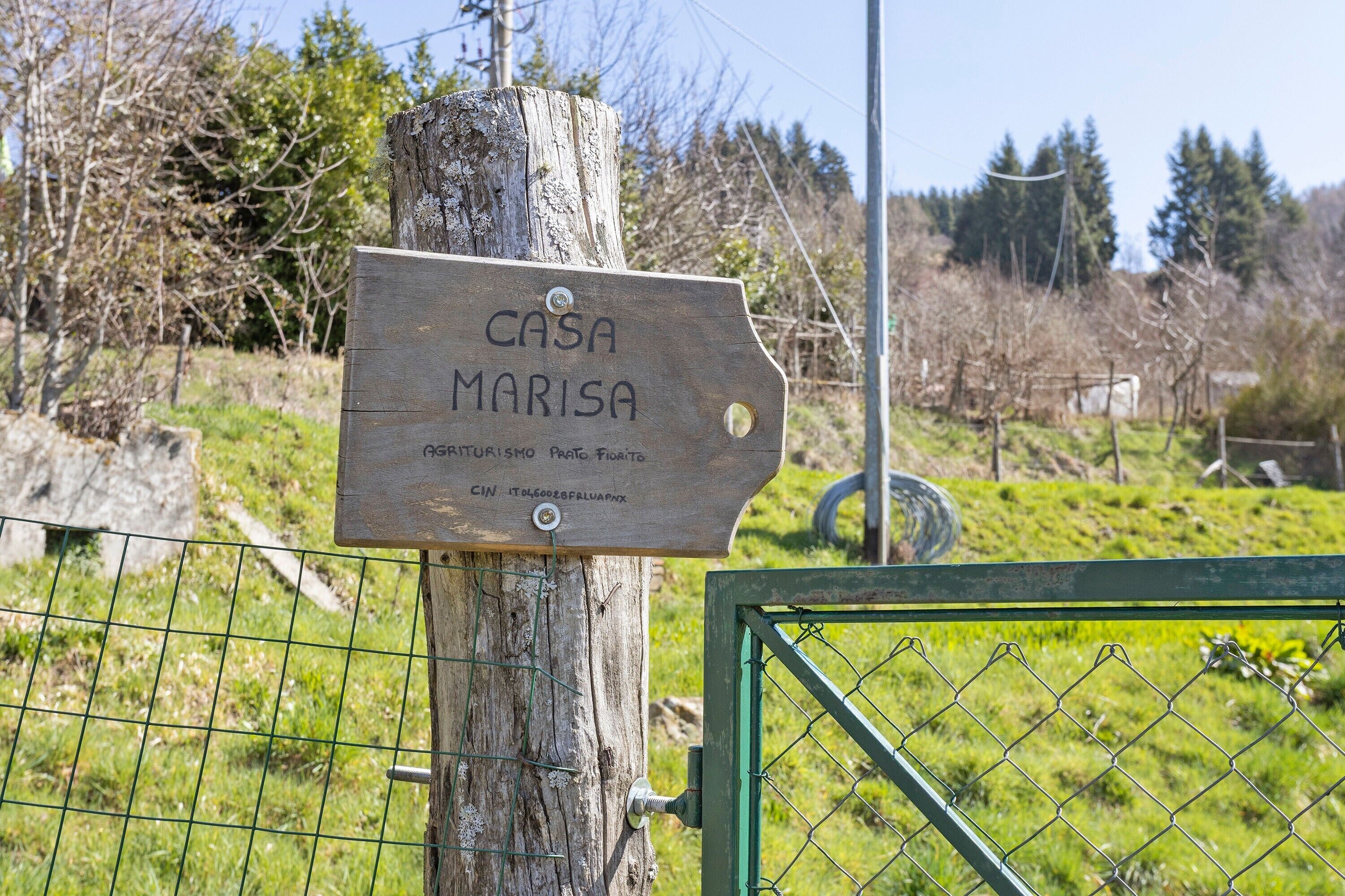 Un letrero de madera con el texto 'CASA MARISA' y texto adicional en otro idioma.