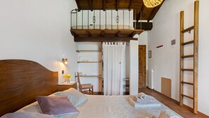 A bedroom with a wooden headboard, a bed with white linens, a nightstand with a lamp, a chair, a wardrobe, and a ladder against the wall. - Room 'Camera B' – Prato Fiorito with Mountain View and Shared Pool (Bagni di Lucca)